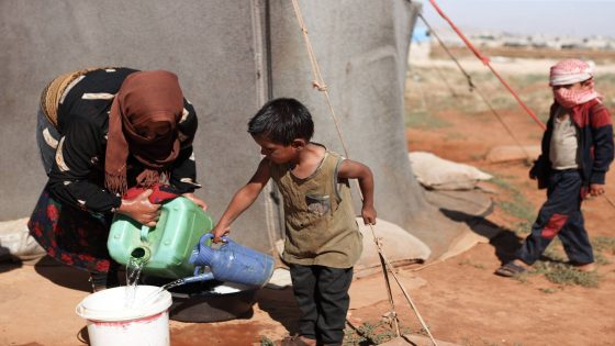 A woman fills a bucket with water at a camp for displaced people near Sarmada in the northern Syrian Idlib province on June 28, 2024. After 13 years of civil conflict, lack of international funding has severely undercut the provision of basic services such as water, waste disposal and sanitation in displacement camps in northwest Syria, according to the United Nations. More than five million people, most of them displaced, live in areas outside government control in Syria's north and northwest, according to the UN, many relying on aid to survive. (Photo by AAREF WATAD / AFP)